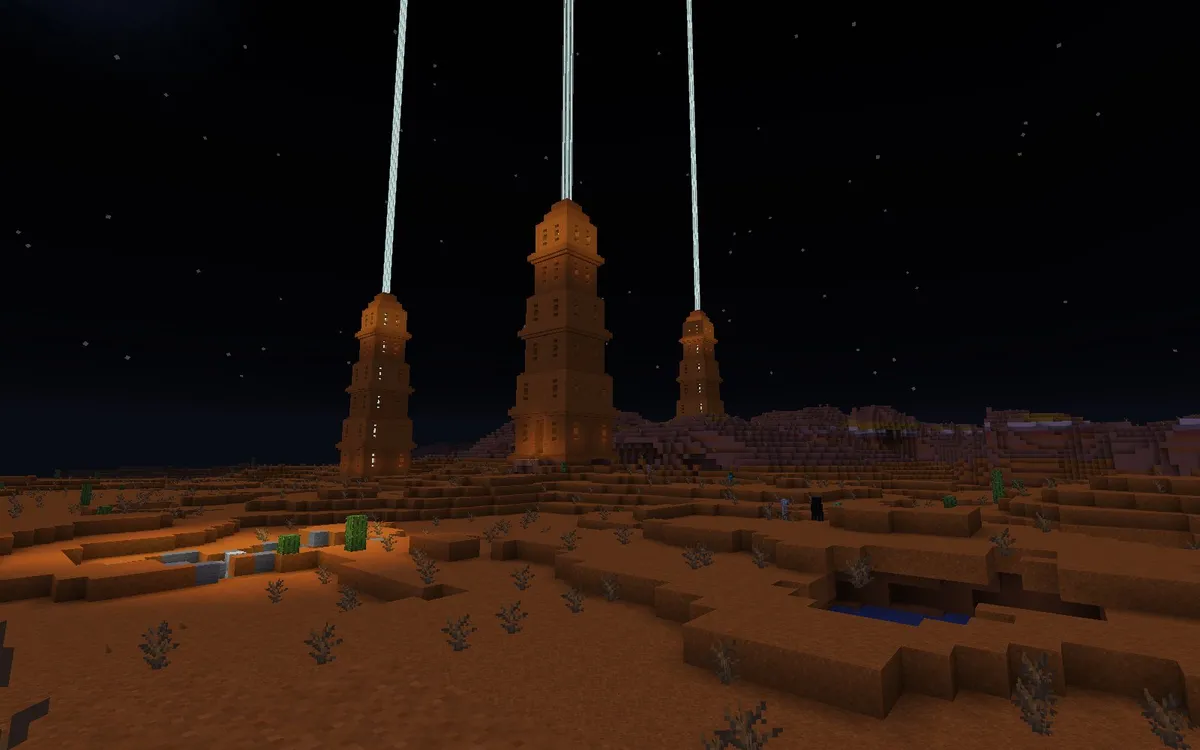 Three tall towers of red sandstone with lit windows standing in a red sand desert at night, each sending a pale blue beacon beam straight up into a starry sky