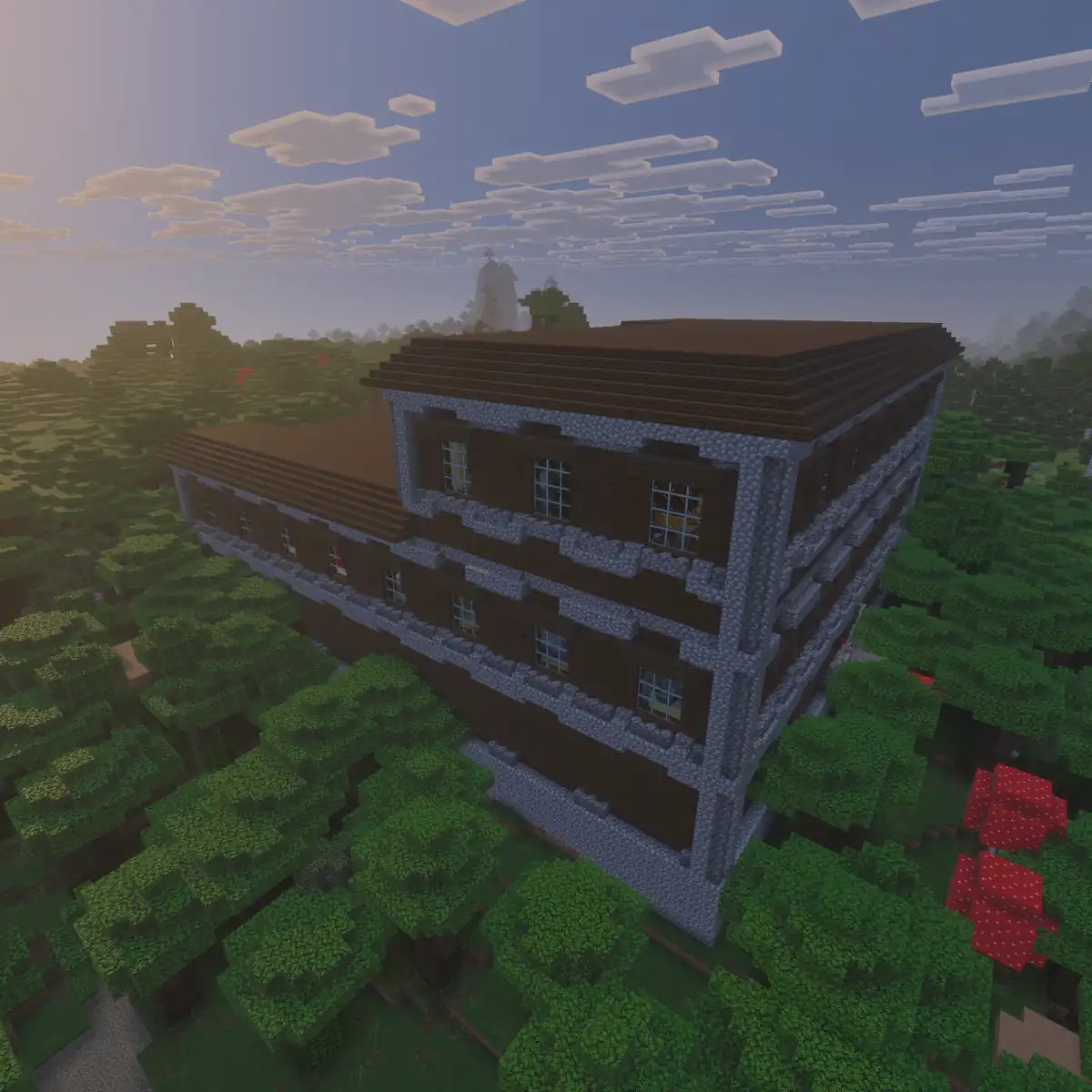 A huge dark oak woodland mansion with cobblestone corners, rows of glass windows and a flat brown roof, rising above a thick dark forest with two red mushrooms under a hazy evening sky