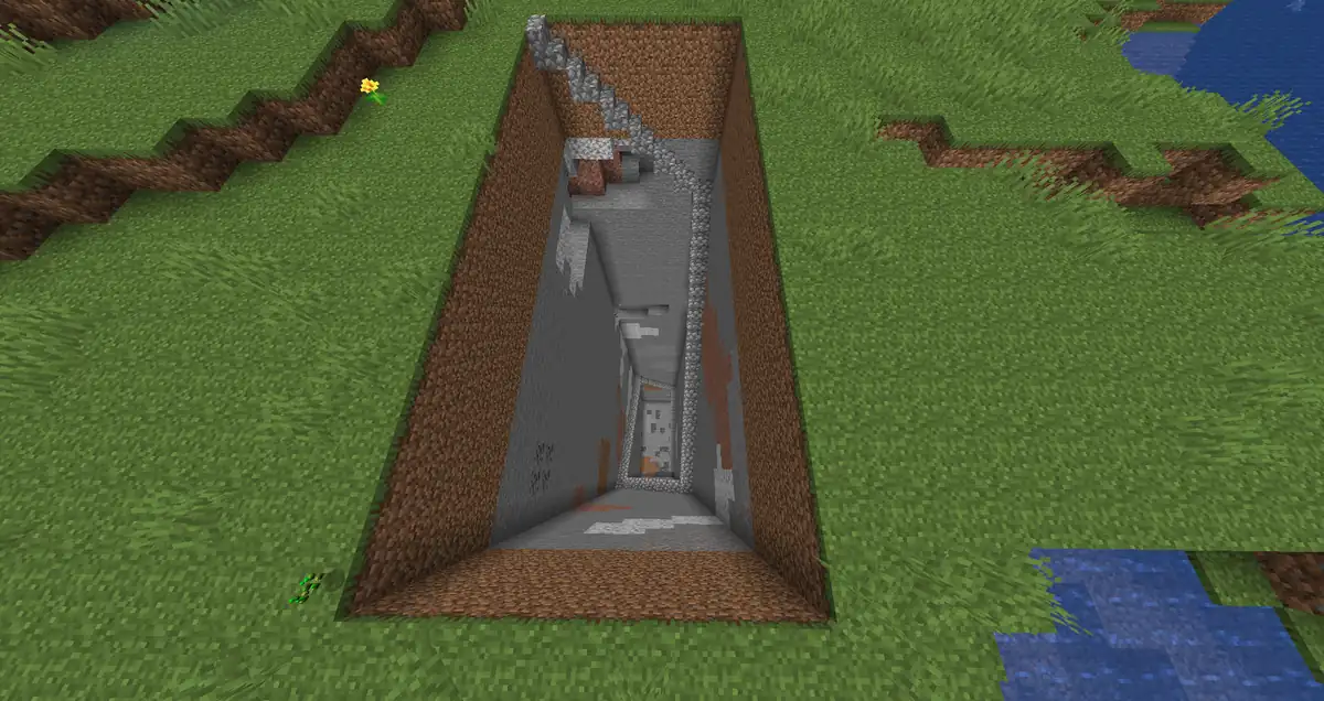 A long rectangular pit dug straight down through grass, dirt and stone, with a cobblestone staircase along one wall and bare stone at the bottom