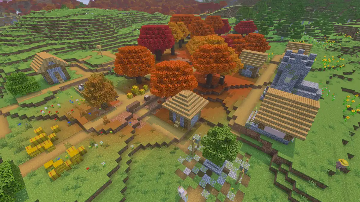A small village of thatched houses and a cobblestone church among bright orange and red autumn trees, with hay bales, paths and green hills around it