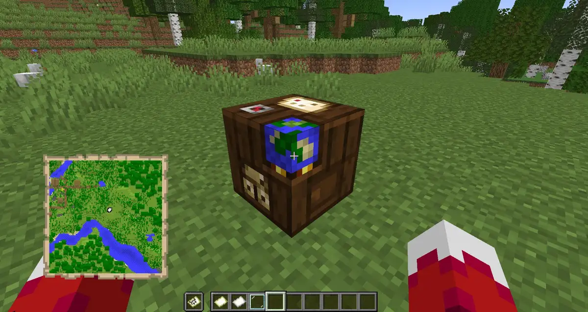 A cartography table on a grass field near a birch and oak forest, seen in first person with a filled map of a river in the player's left hand
