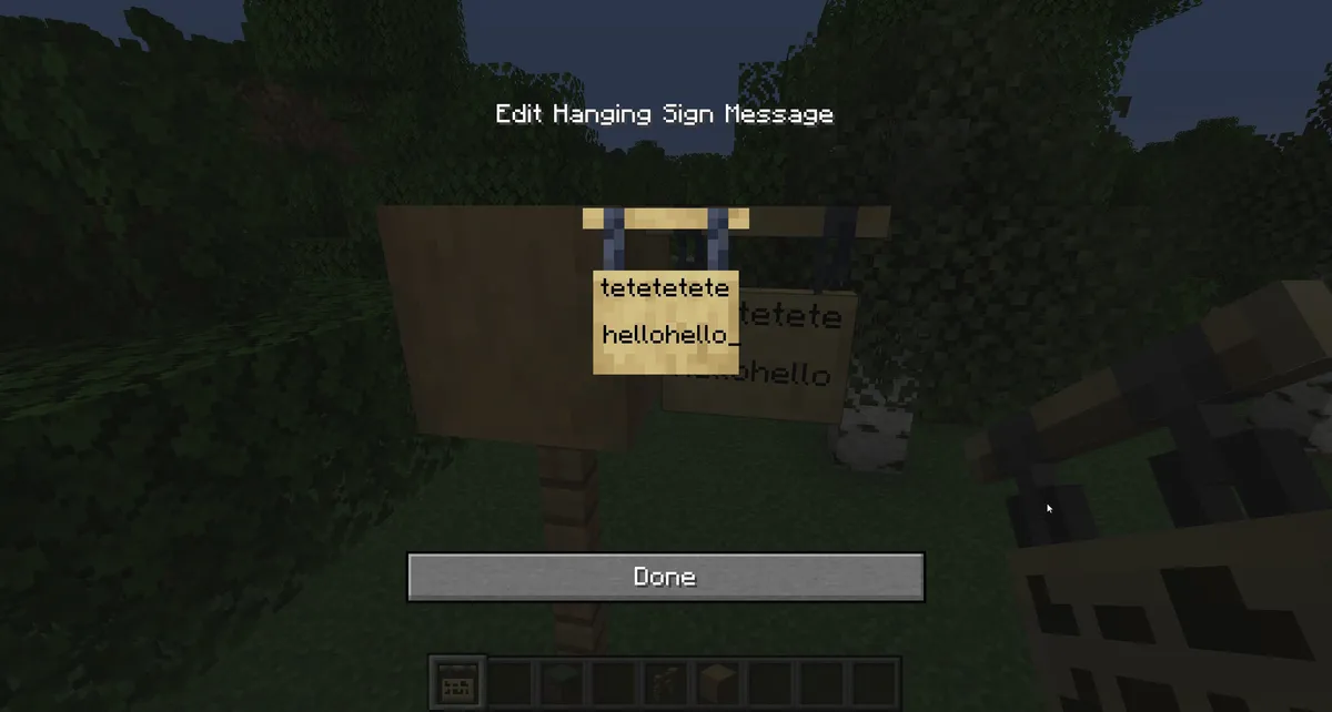 The Edit Hanging Sign Message screen in Minecraft Java Edition, with text being typed onto a hanging sign in a dark forest and a Done button underneath