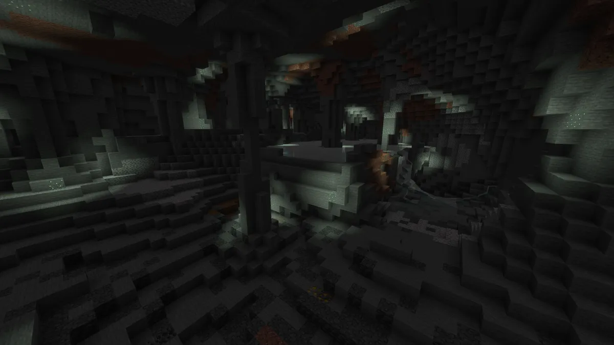A large dark cave with tall stone pillars and uneven floors, where patches of ore show in the walls in the dim light