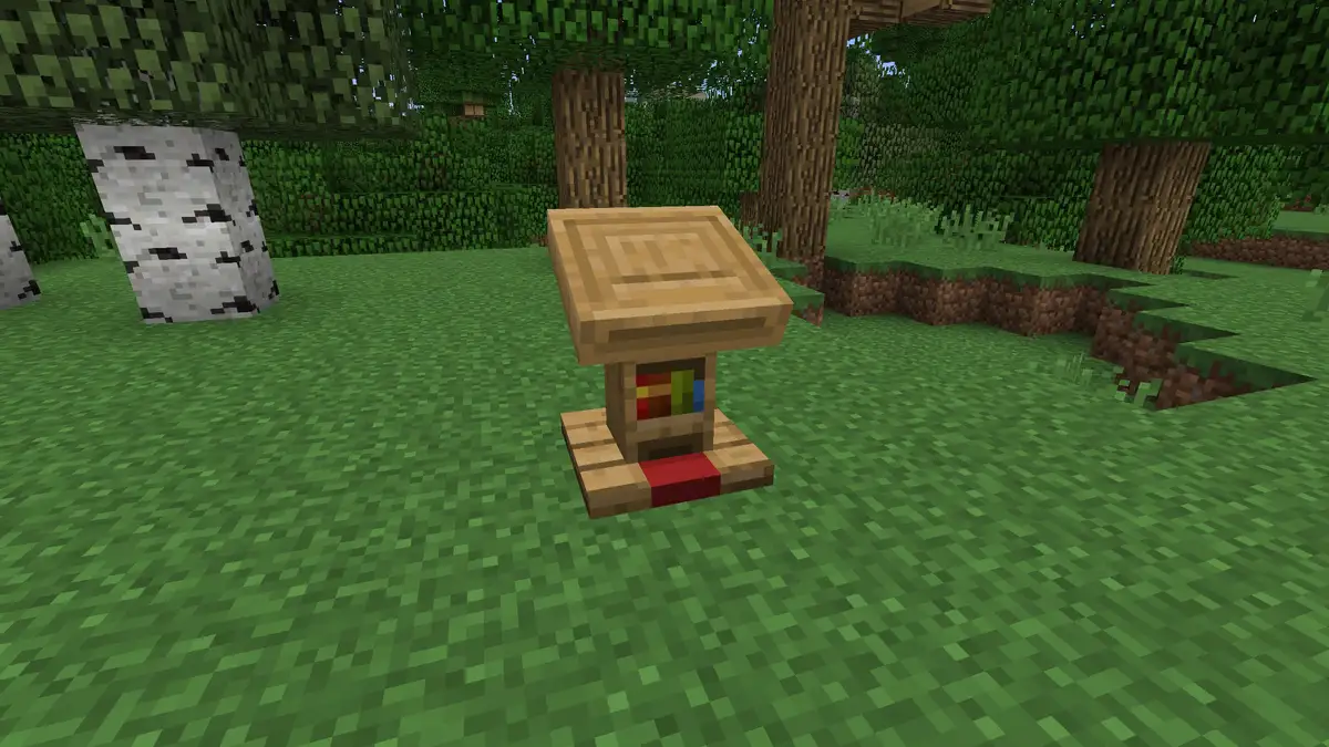 A single oak lectern standing on grass in a forest of birch and oak trees, with colourful book spines on the front of its base